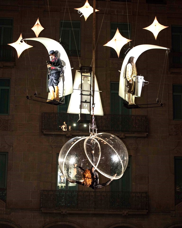 Artistas flotan en el aire entre luces y sueños en la noche.