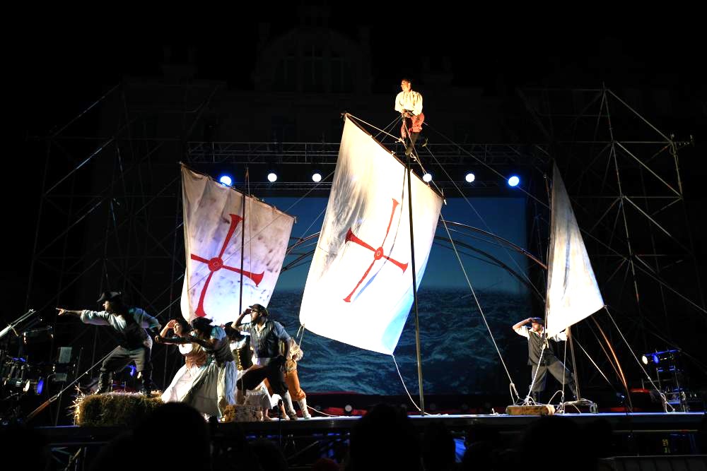 Espectáculo teatral con mástil chino y artistas simulando un barco de vela.