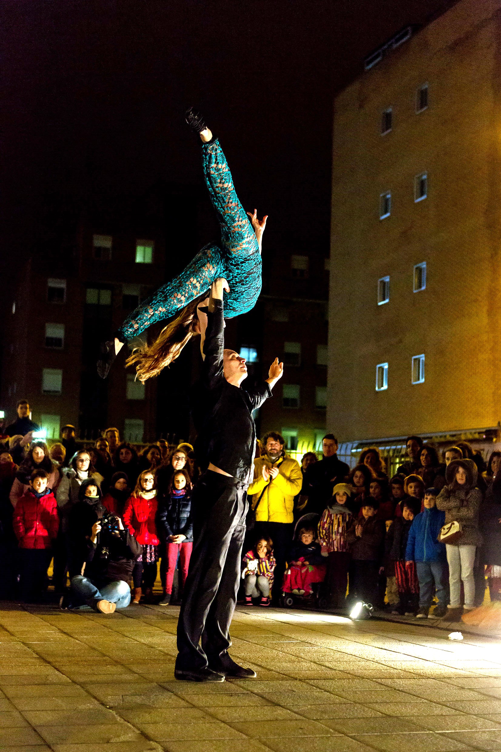 Un acróbata sostiene en vilo a su compañera, quien realiza una pose vertical invertida.