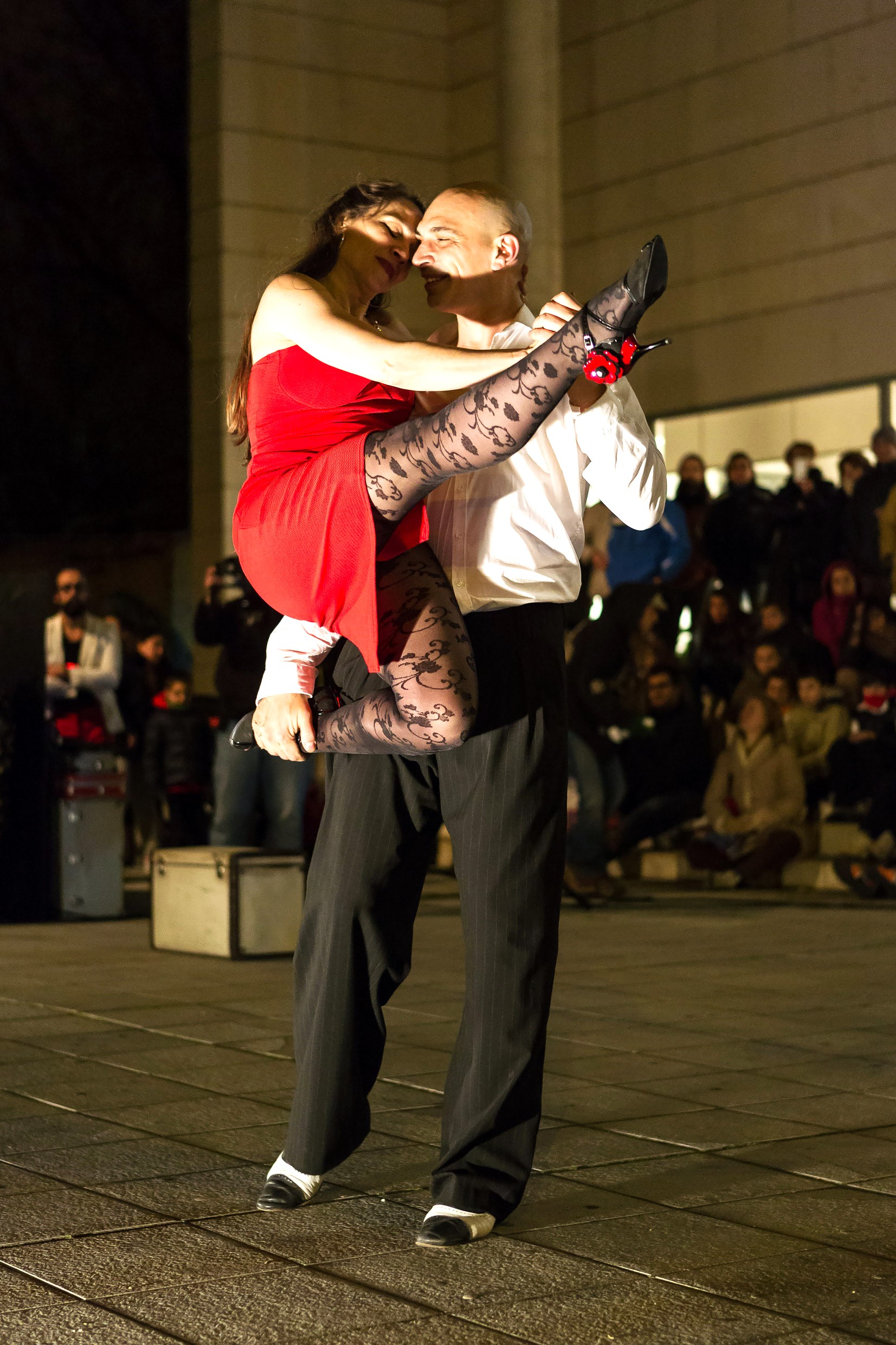 Pareja de tango en una plaza iluminada.