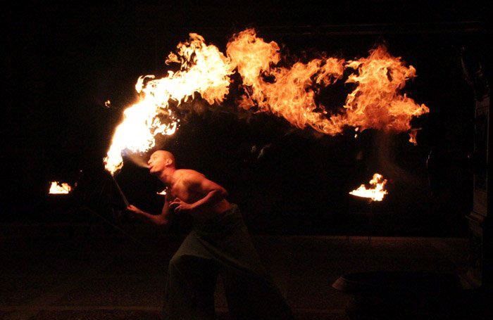 El artista, con el torso descubierto, expulsa una impresionante ráfaga de fuego hacia el cielo.