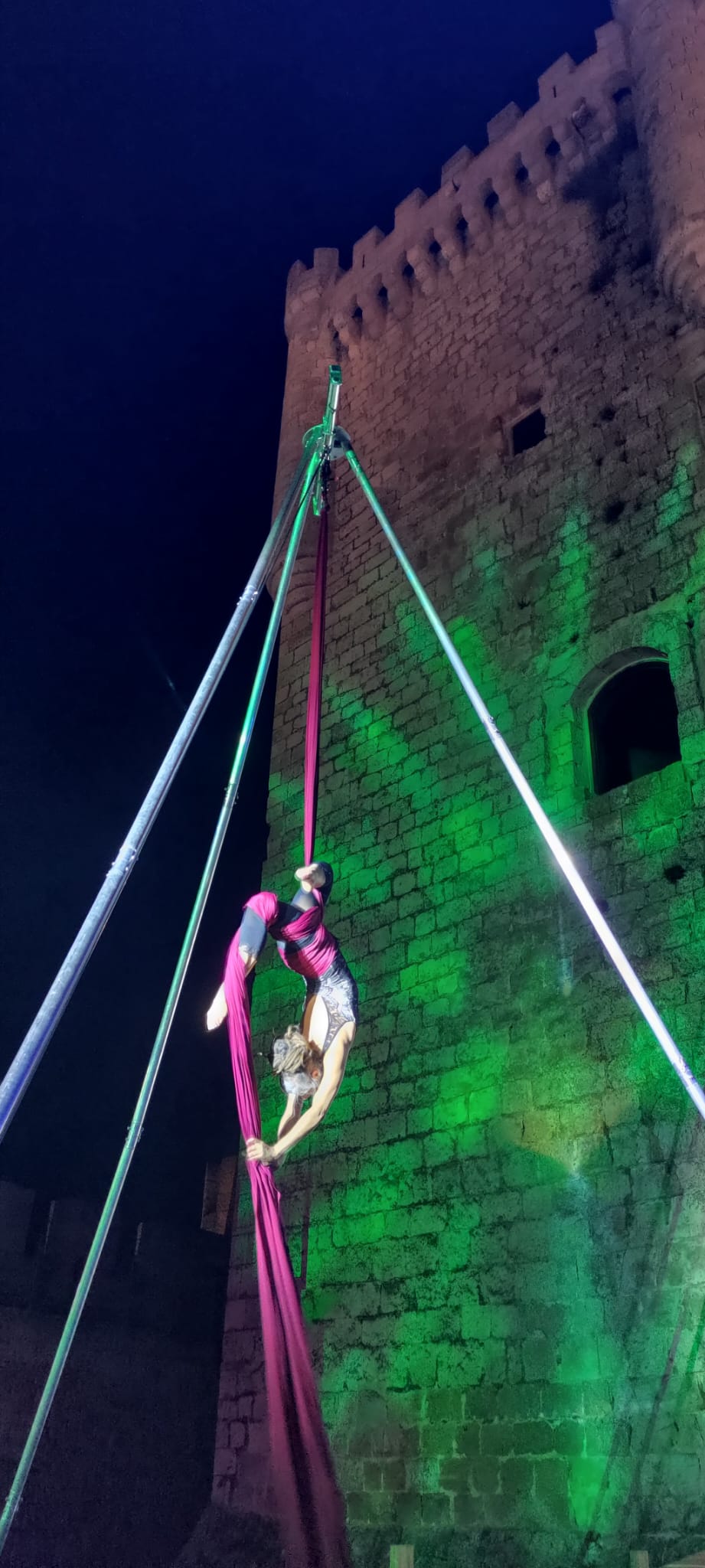 Artista de circo con telas aéreas en un castillo.
