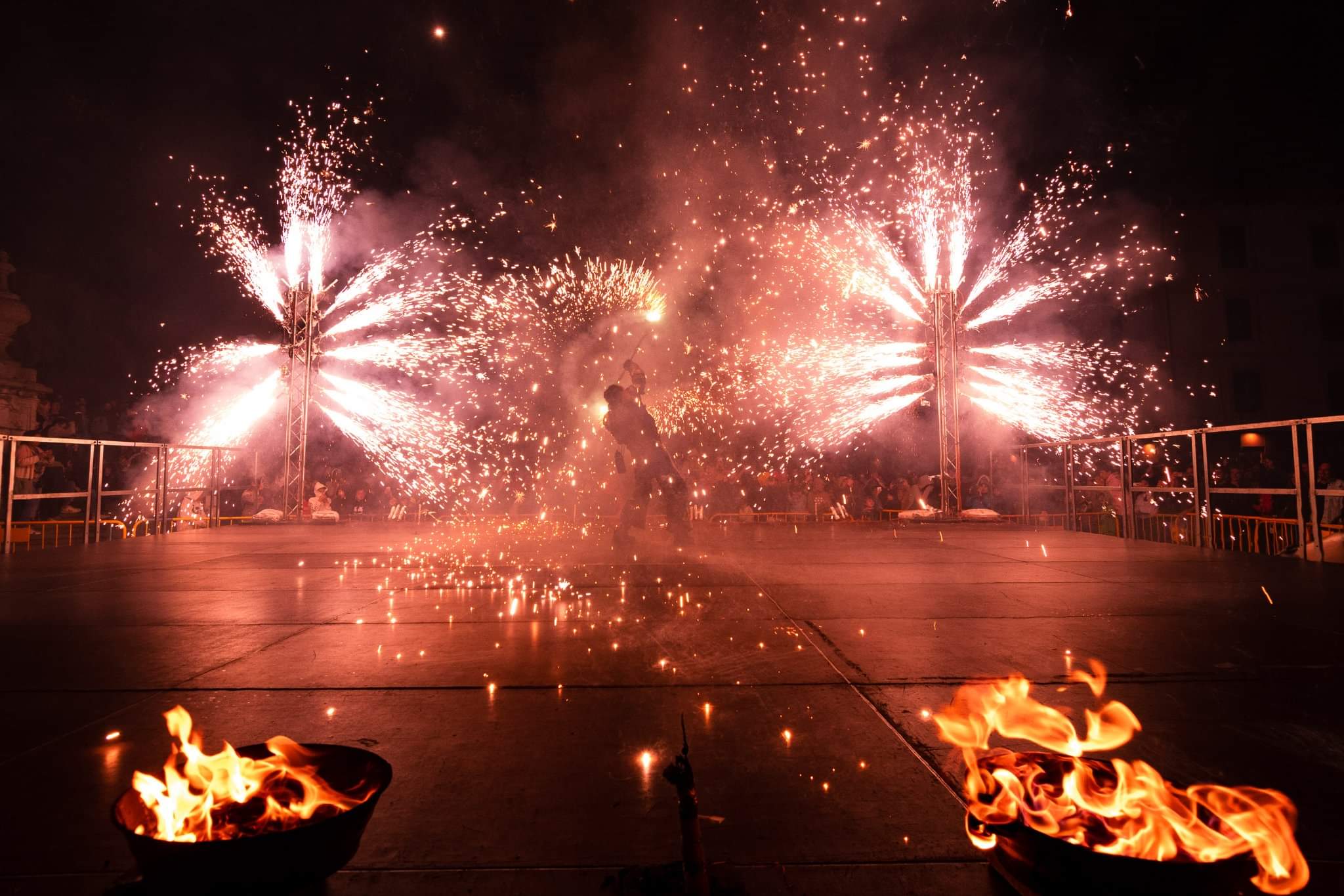 Un artista danza entre cascadas de chispas y lenguas de fuego que iluminan la noche.