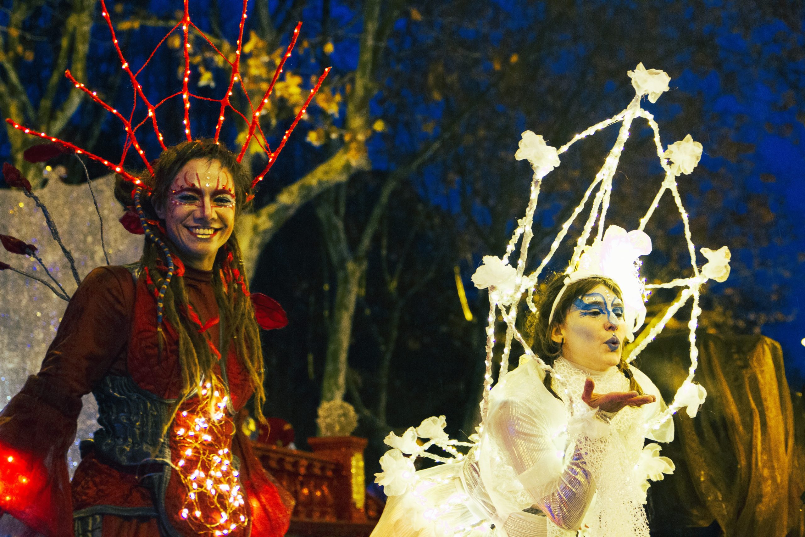 Dos artistas con atuendos de fantasía iluminados por LED.