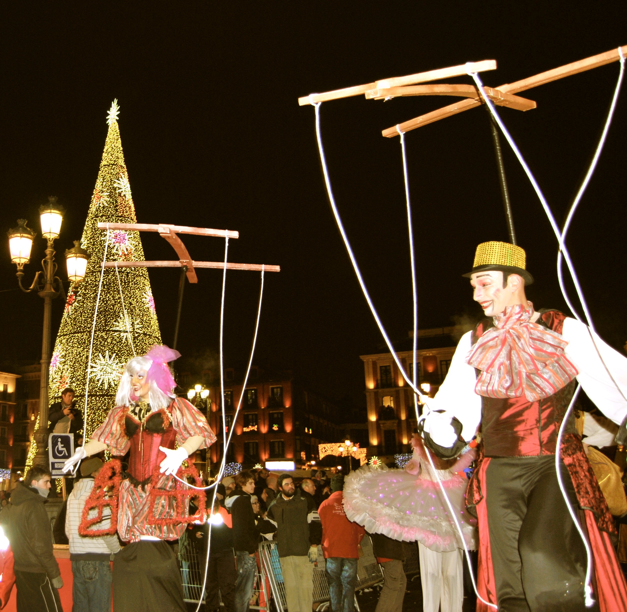 Zancudos con atuendos de época actúan como marionetas gigantes bajo crucetas de madera.