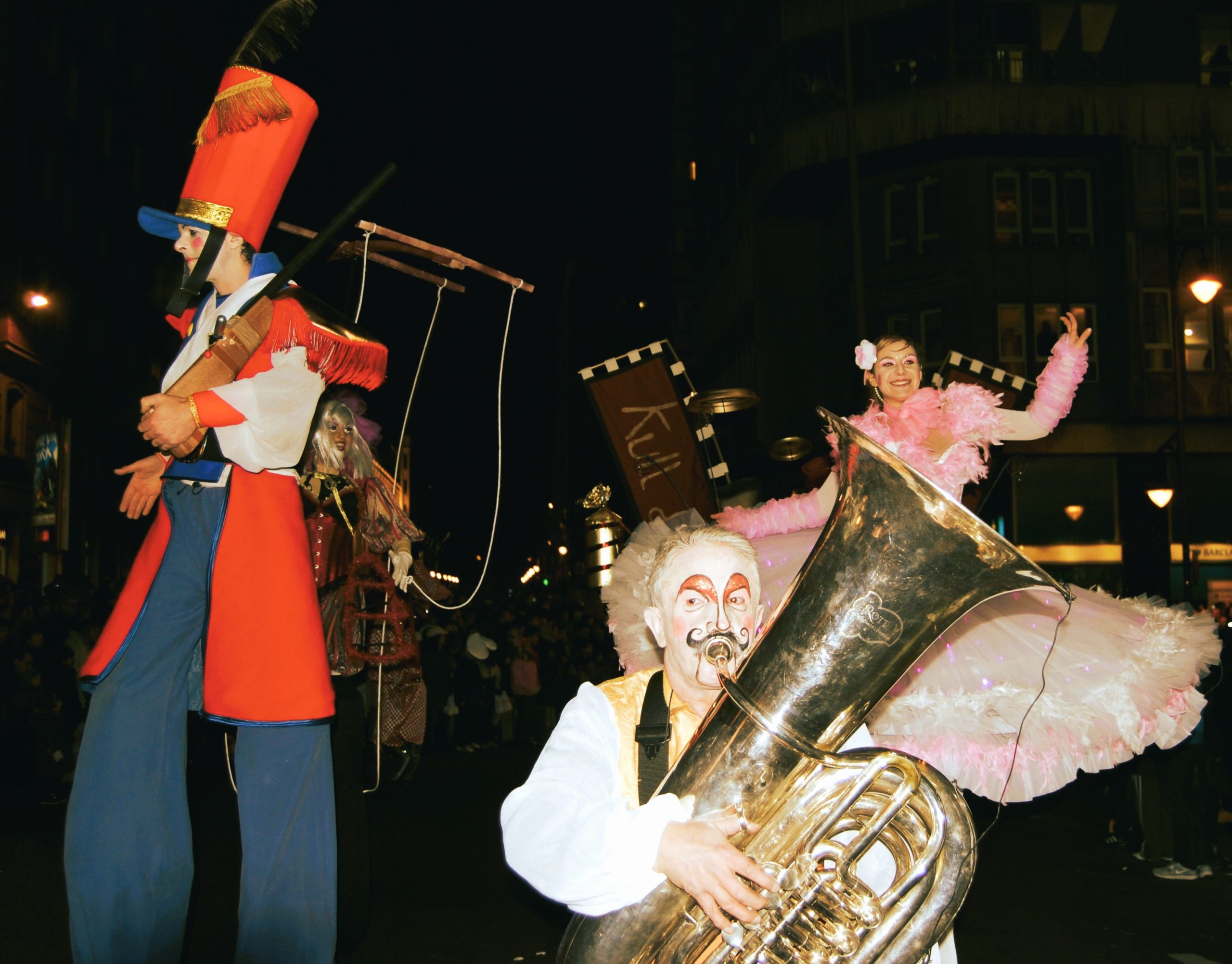 Un músico con rostro caracterizado toca una gran tuba dorada.
