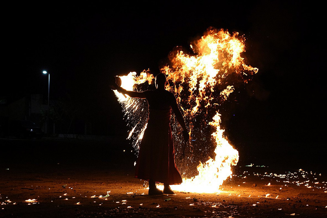 La silueta de un artista, envuelta en sombras, manipula una antorcha que genera una gran llamarada