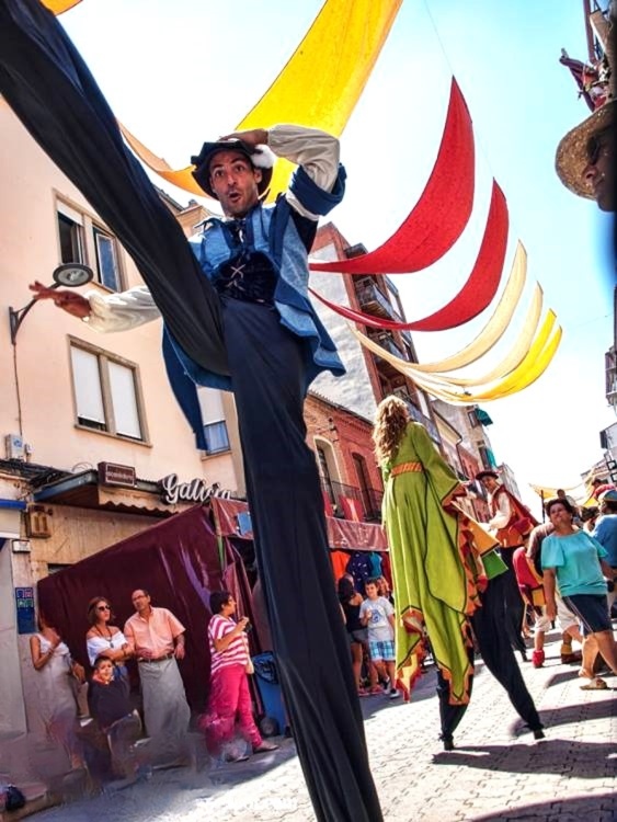 Zancudo con traje azul y pantalón negro hace un paso alto y largo en una calle soleada.